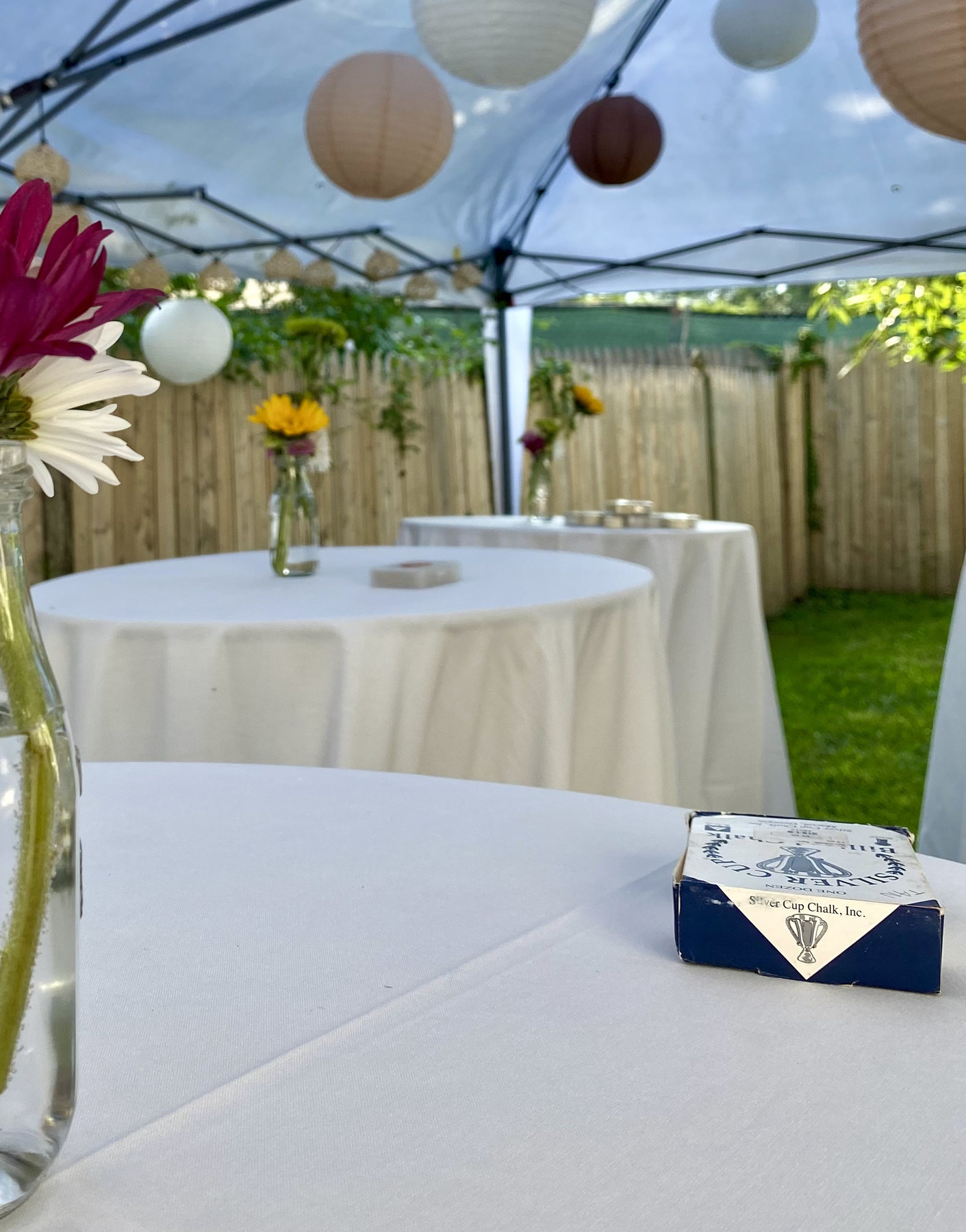 Outdoor event tables arranged beneath a canopy and paper lanterns