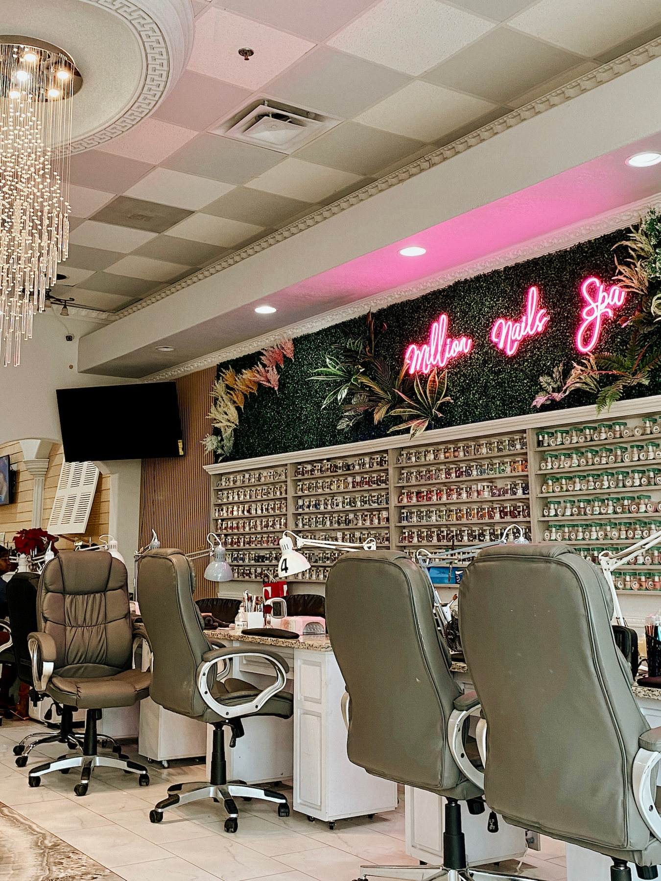 Nail salon stations beneath a pink neon sign