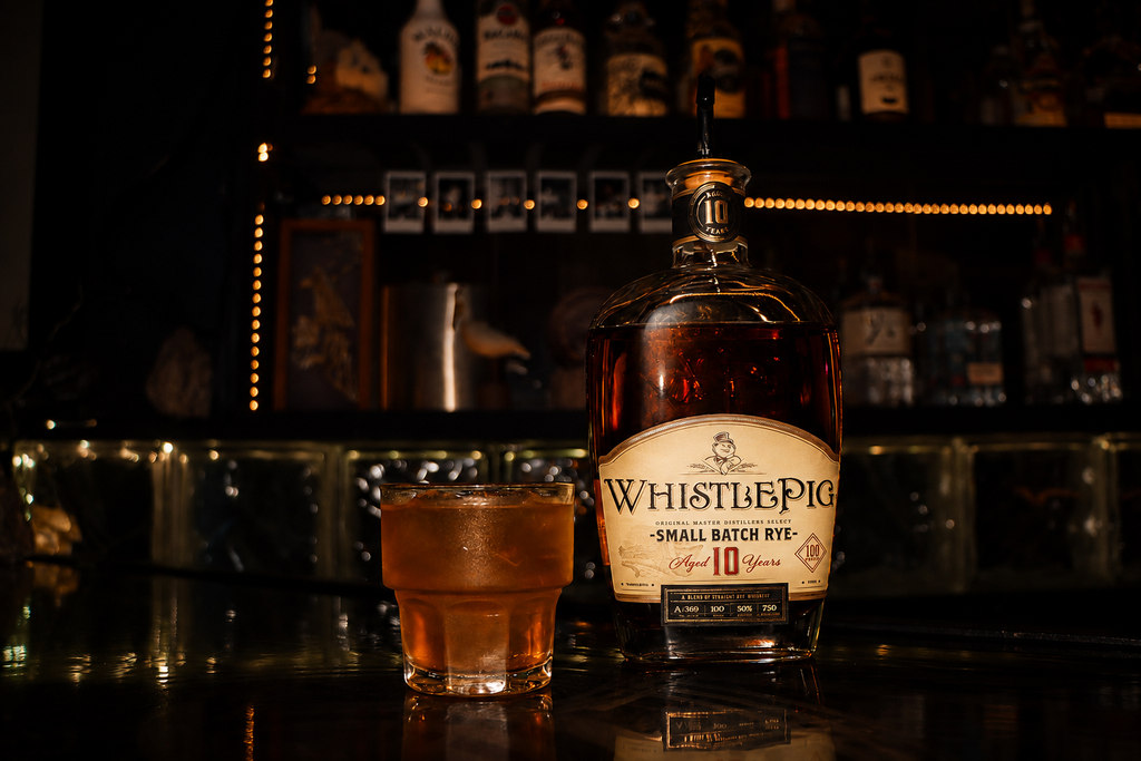 Whiskey bottle and cocktail photographed in a dimly lit bar