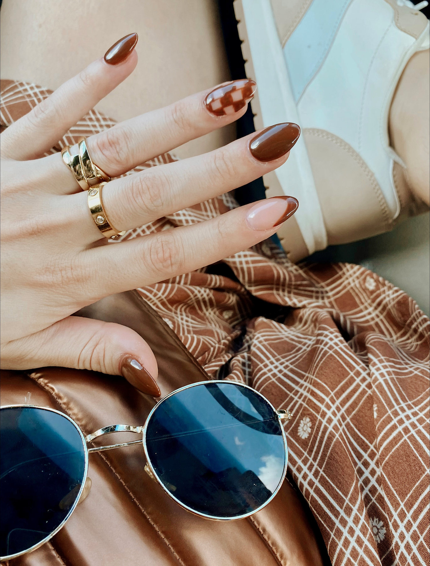 Brown and blush nail art with gold rings and sunglasses
