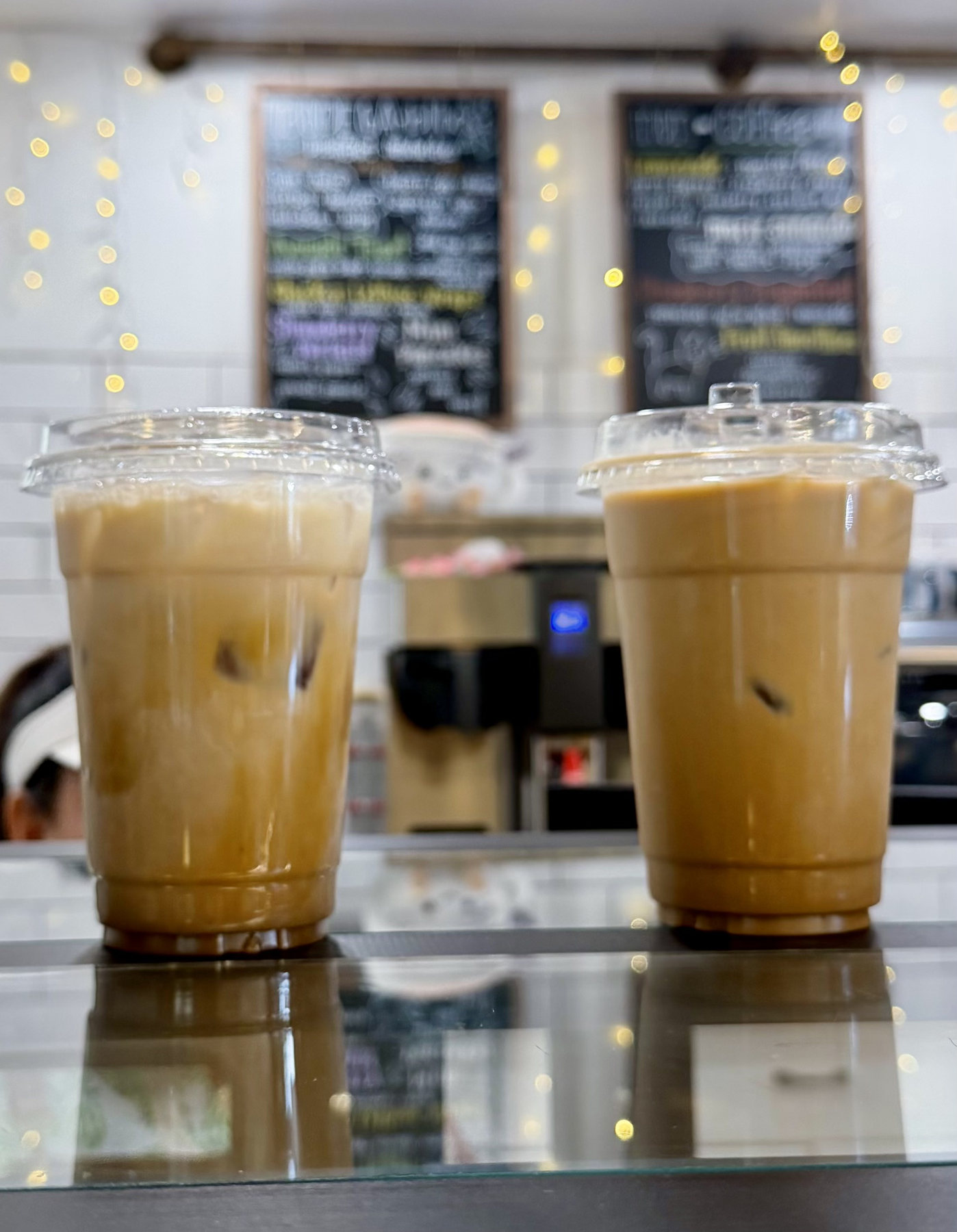 Two iced coffees on a reflective counter